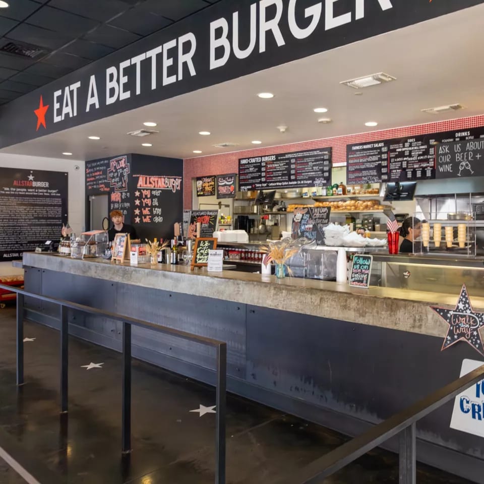 Interior view of Allstar Burger restaurant, showing the service counter, menu boards, and kitchen area.